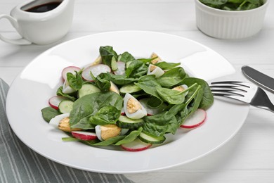 Delicious salad with boiled eggs, radish and spinach on white wooden table, closeup