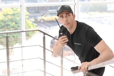 Photo of Male security guard with portable radio transmitter indoors