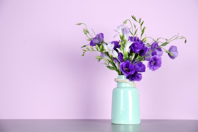 Photo of Vase with beautiful flowers on table against color background. Space for text