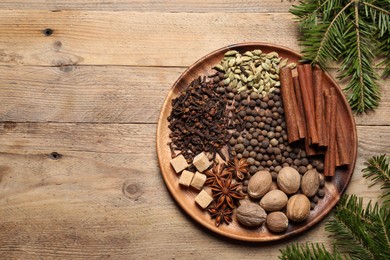 Photo of Different spices, nuts and fir branches on wooden table, flat lay. Space for text