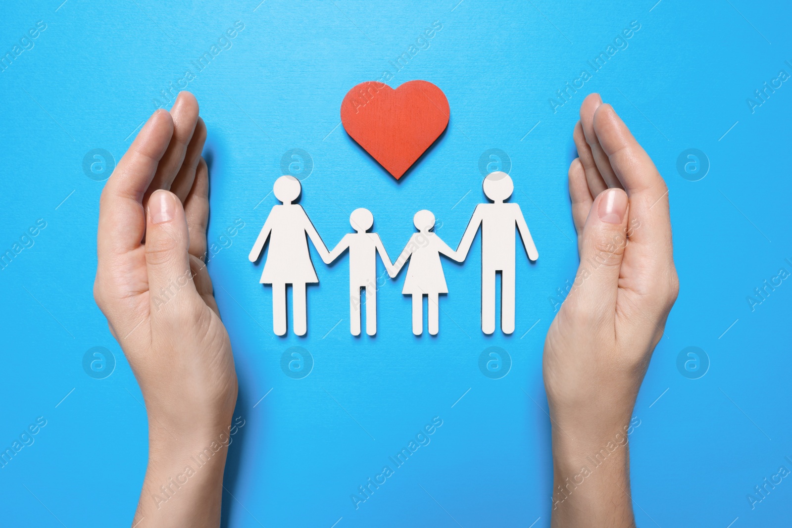 Photo of Woman protecting figures of family on light blue background, top view. Insurance concept