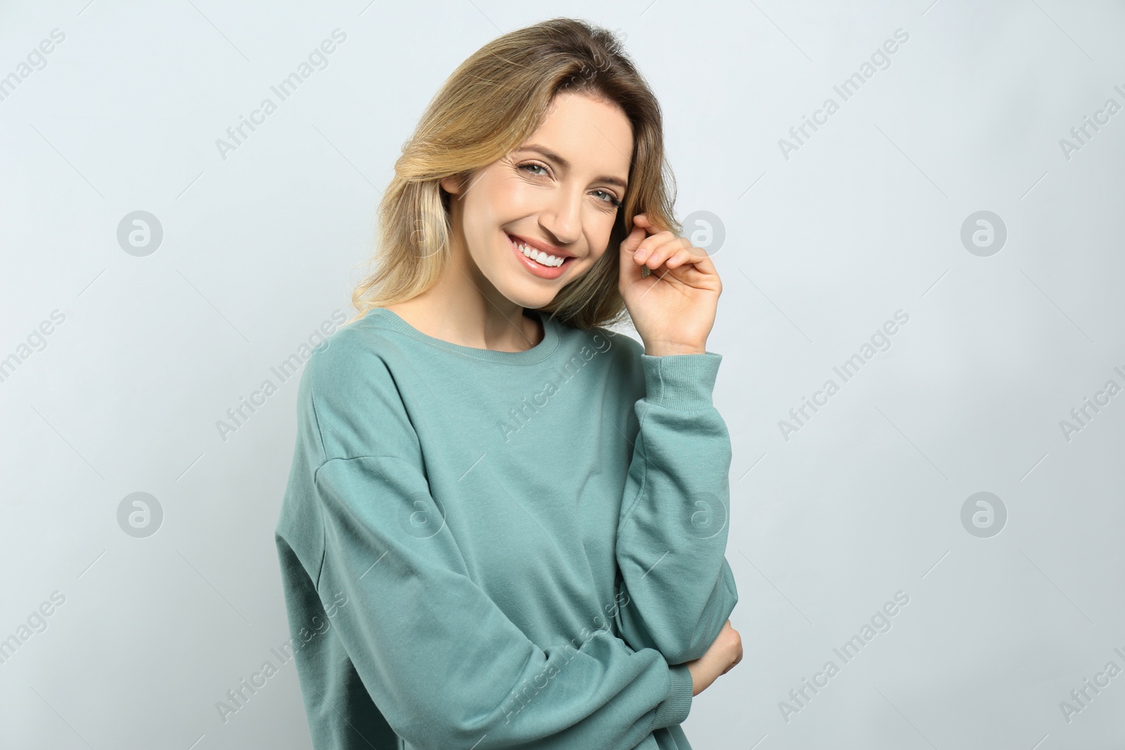 Photo of Portrait of happy young woman with beautiful blonde hair and charming smile on light background