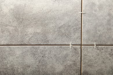 Photo of Stylish tiles with spacers on wall in room