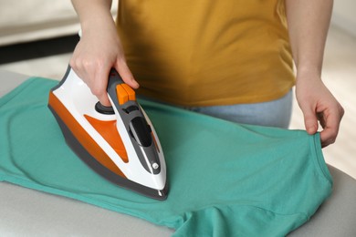 Photo of Woman ironing clean shirt at home, closeup