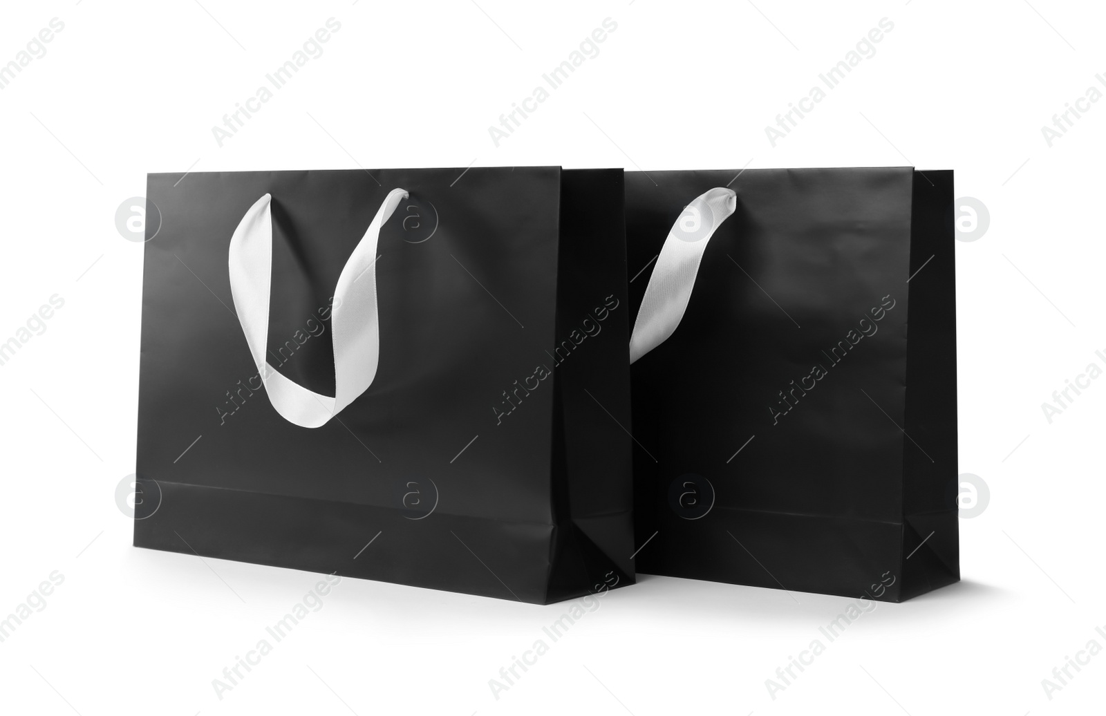 Photo of Paper shopping bags with ribbon handles on white background. Mockup for design