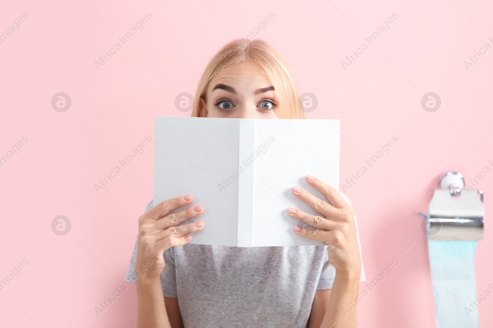 Photo of Young woman with book in toilet room