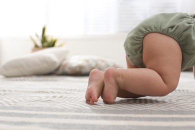 Photo of Cute baby crawling on floor at home, closeup