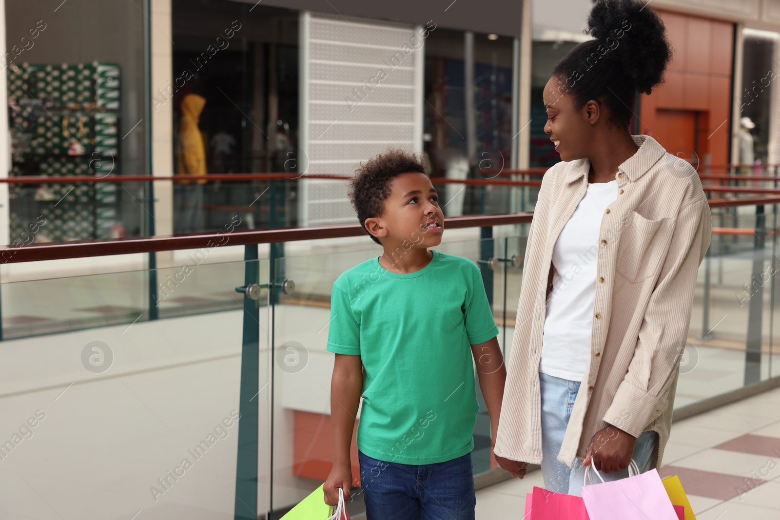 Photo of Family shopping. Happy mother and son with colorful bags in mall