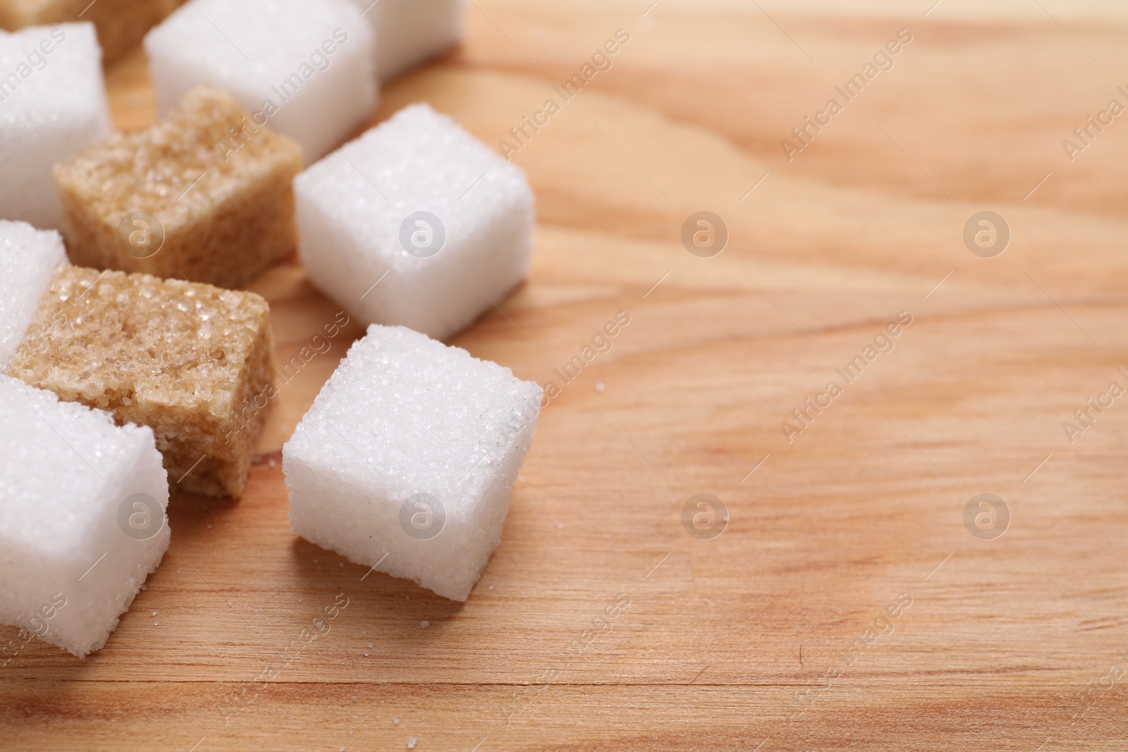 Photo of White and brown sugar cubes on wooden table, closeup. Space for text