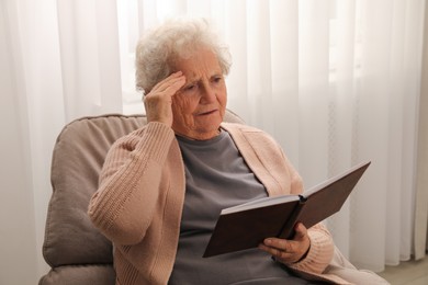 Senior woman with notebook at home. Age-related memory impairment