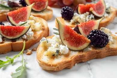 Photo of Bruschettas with cheese, figs and blackberries served on white table, closeup