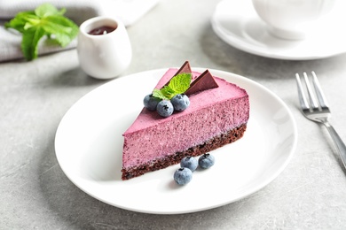 Plate with piece of tasty blueberry cake on gray table