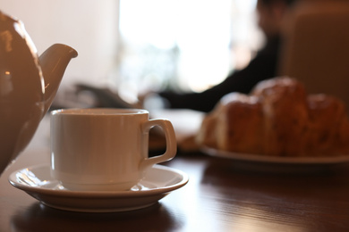 Delicious morning coffee and croissant served for breakfast on wooden table