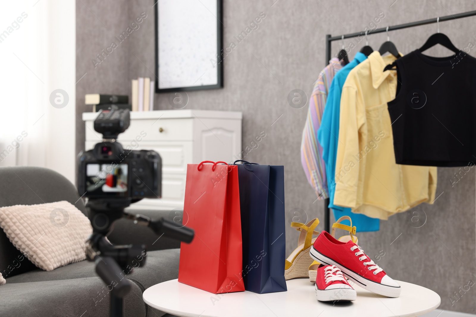 Photo of Fashion blogger's workplace. Shoes, clothes, camera and stylish furniture indoors