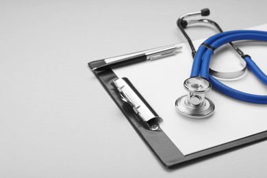 Photo of Stethoscope and clipboard on white background, closeup. Space for text