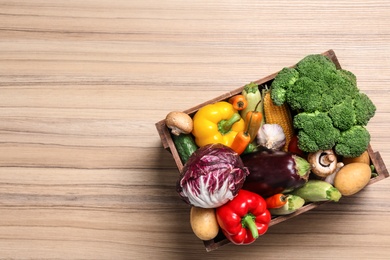 Photo of Crate with different fresh vegetables on wooden background, top view. Space for text