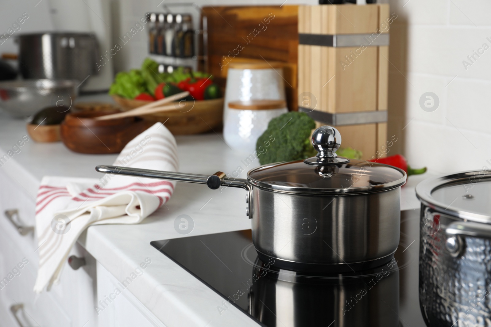 Photo of Metal saucepan on cooktop in kitchen. Cooking utensils