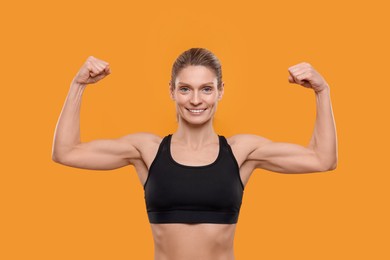 Photo of Portraitsportswoman showing muscles on yellow background