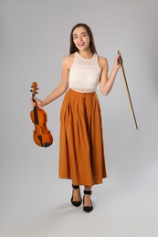 Beautiful woman with violin on grey background