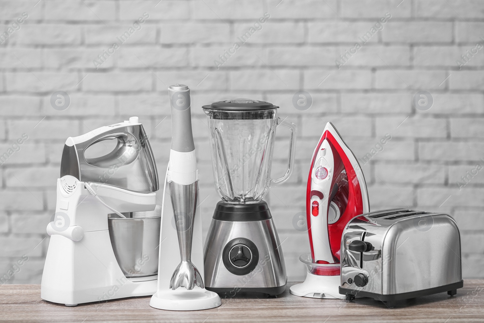 Photo of Household and kitchen appliances on table against brick wall background. Interior element