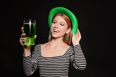 Young woman with green beer on black background. St. Patrick's Day celebration