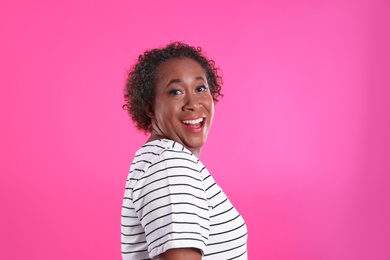 Portrait of happy African-American woman on pink background