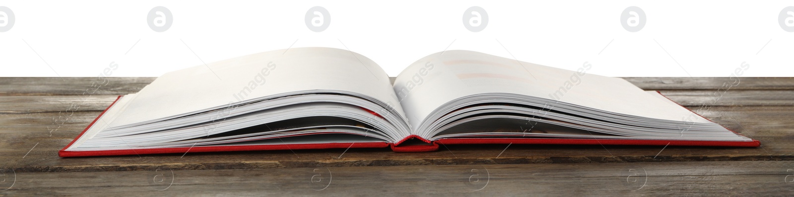 Photo of Open book with red cover on wooden table against white background