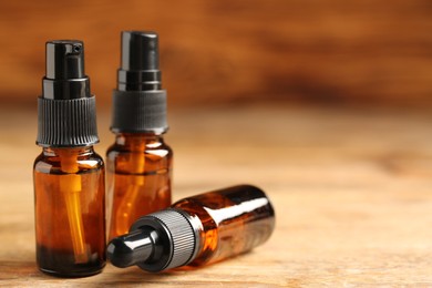 Photo of Bottles of oil on wooden table, closeup with space for text. Natural cosmetics