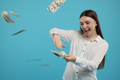 Happy woman throwing money on light blue background