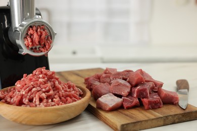 Photo of Electric meat grinder with beef on white table indoors