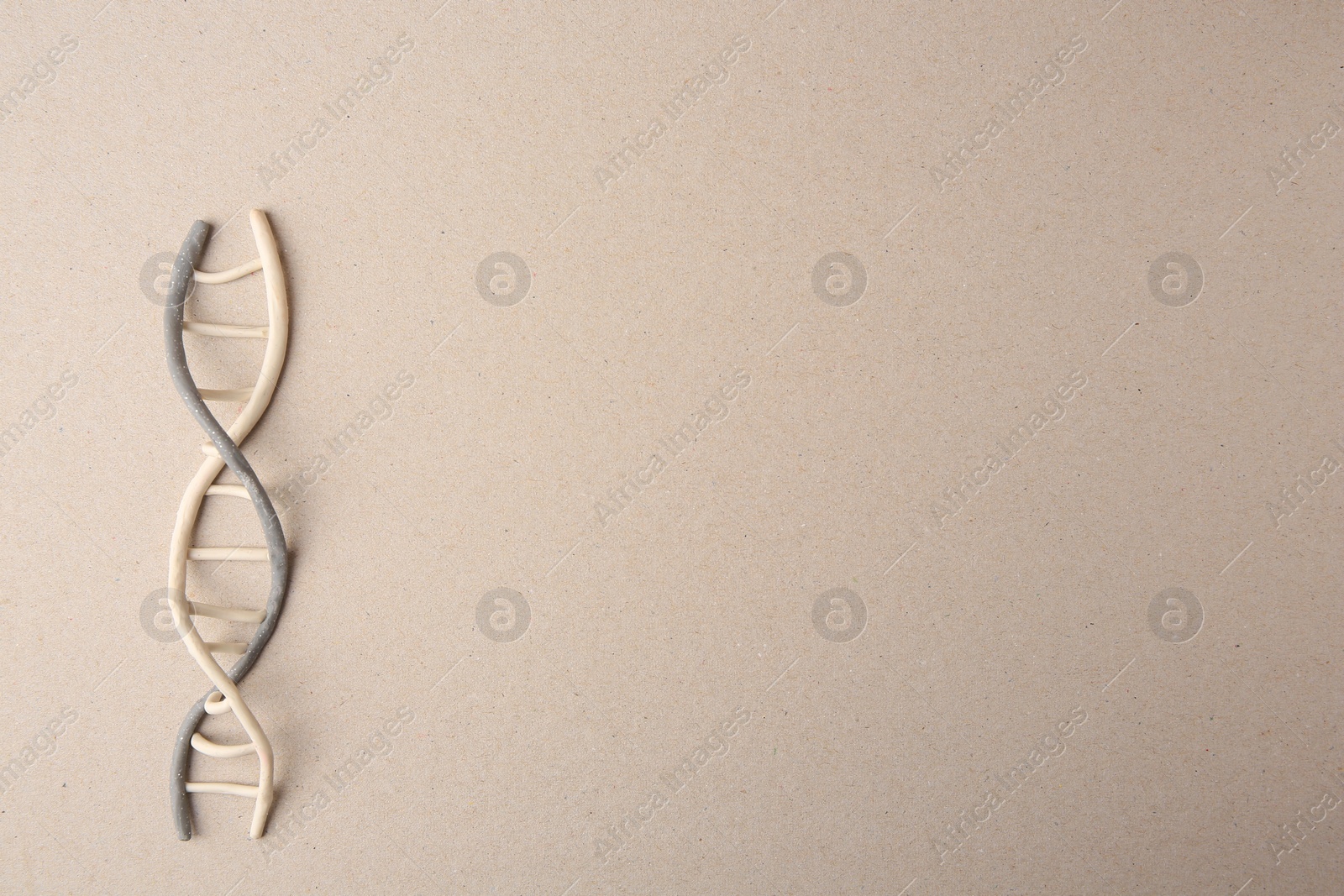 Photo of Plasticine model of DNA molecular chain on beige background, top view. Space for text