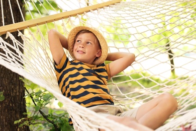 Photo of Little boy resting in hammock outdoors. Summer camp