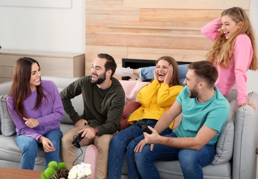 Photo of Group of friends laughing while playing video game in living room