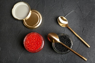 Glass jars with black and red caviar on grey background