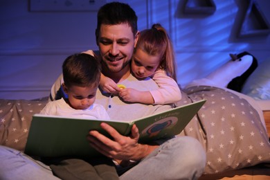 Photo of Father reading bedtime story to his children at home