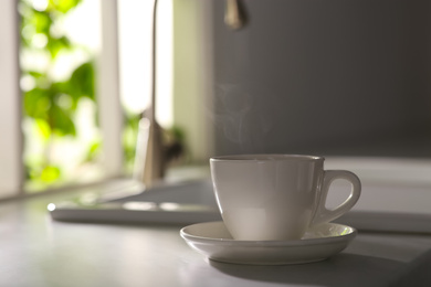 Photo of Cup of delicious coffee on kitchen countertop, space for text. Good morning