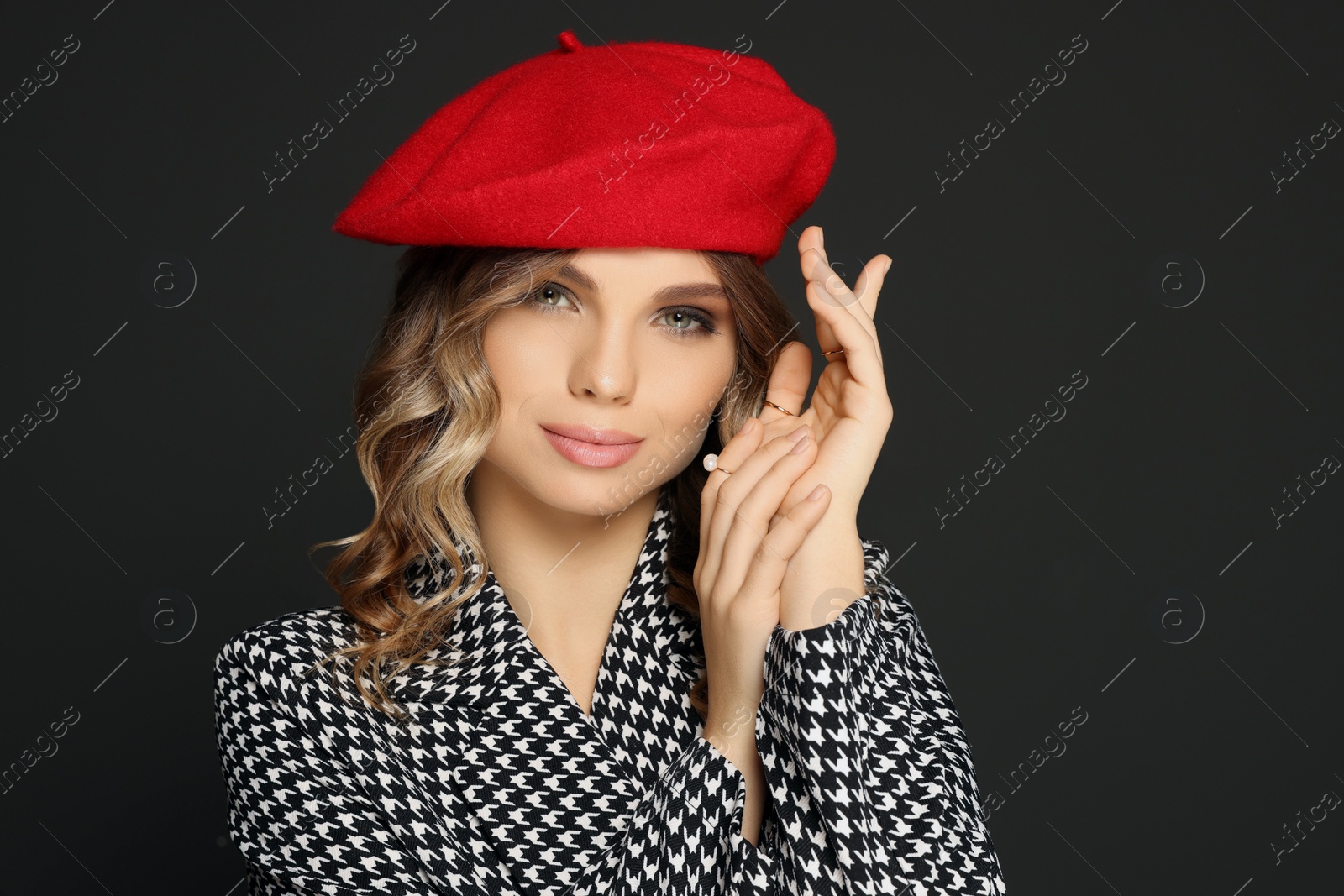 Photo of Young woman with beautiful makeup in red beret against black background