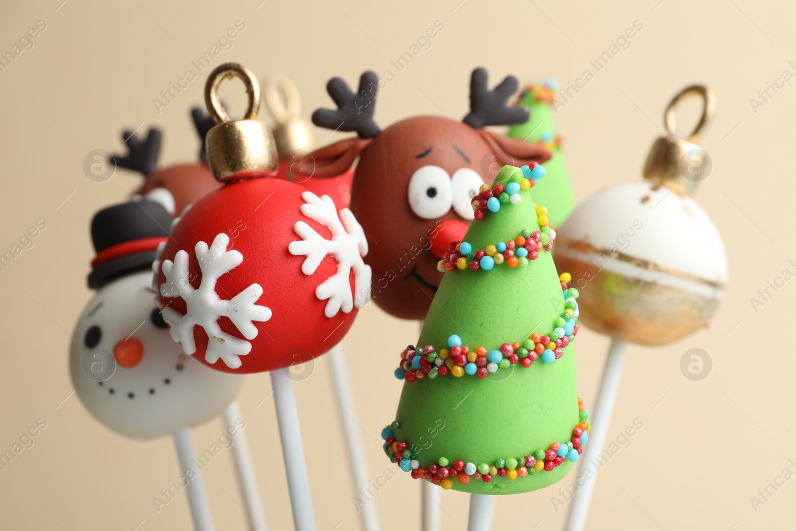 Photo of Delicious Christmas themed cake pops on beige background, closeup