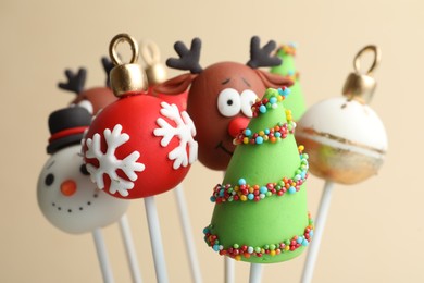 Delicious Christmas themed cake pops on beige background, closeup