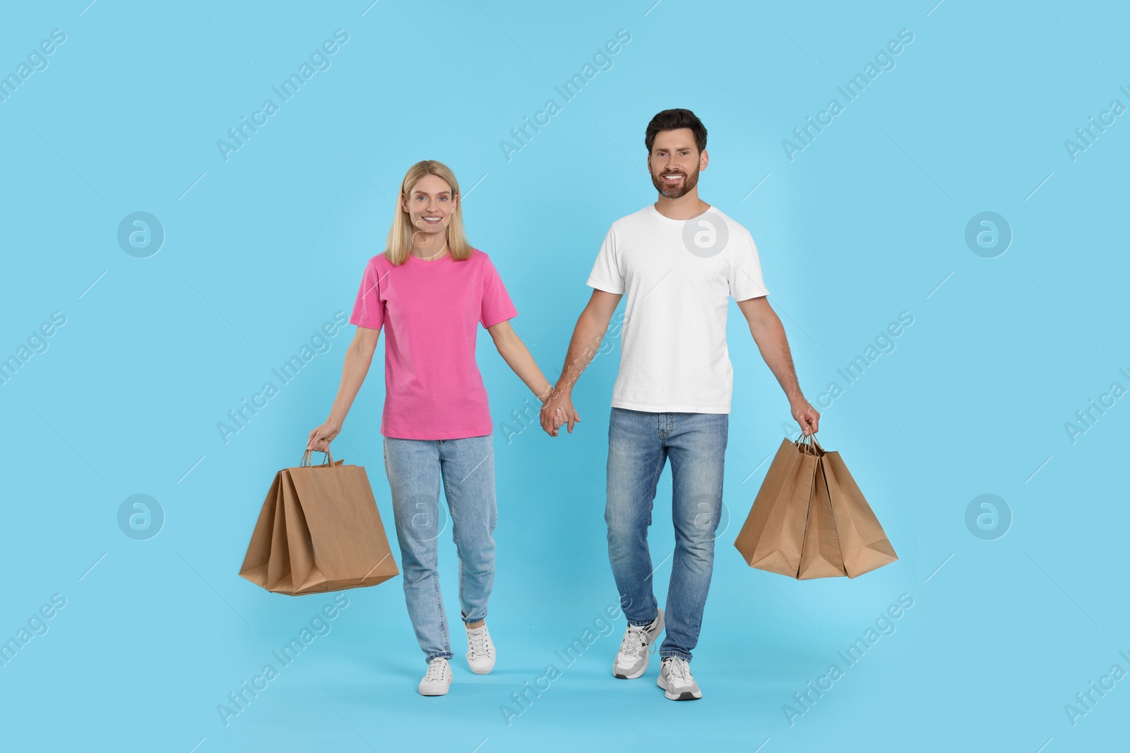 Photo of Family shopping. Happy couple with many paper bags on light blue background