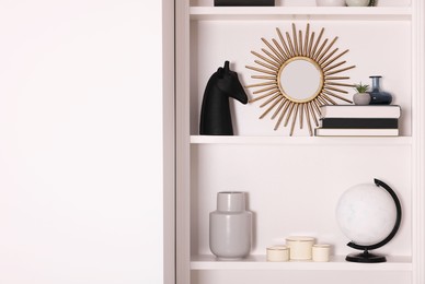 Photo of Interior design. Shelves with stylish accessories and books near white wall. Space for text