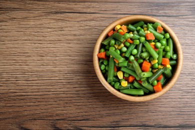 Mix of fresh vegetables in bowl on wooden table, top view. Space for text