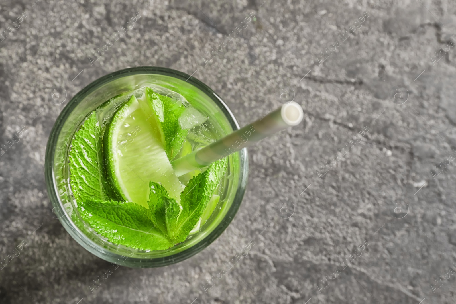 Photo of Refreshing beverage with mint and lime in glass on grey background, top view