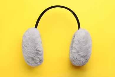 Photo of Stylish winter earmuffs on yellow background, top view