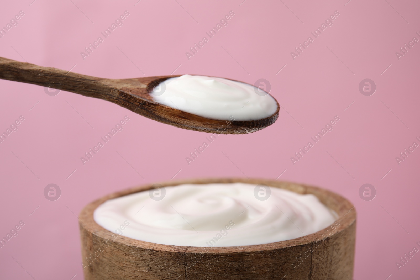 Photo of Eating delicious natural yogurt on pink background, closeup