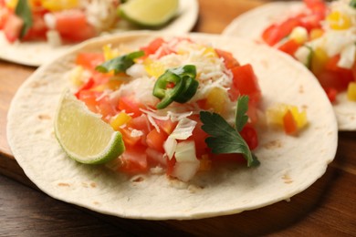 Delicious tacos with vegetables, lime and parsley on wooden table, closeup