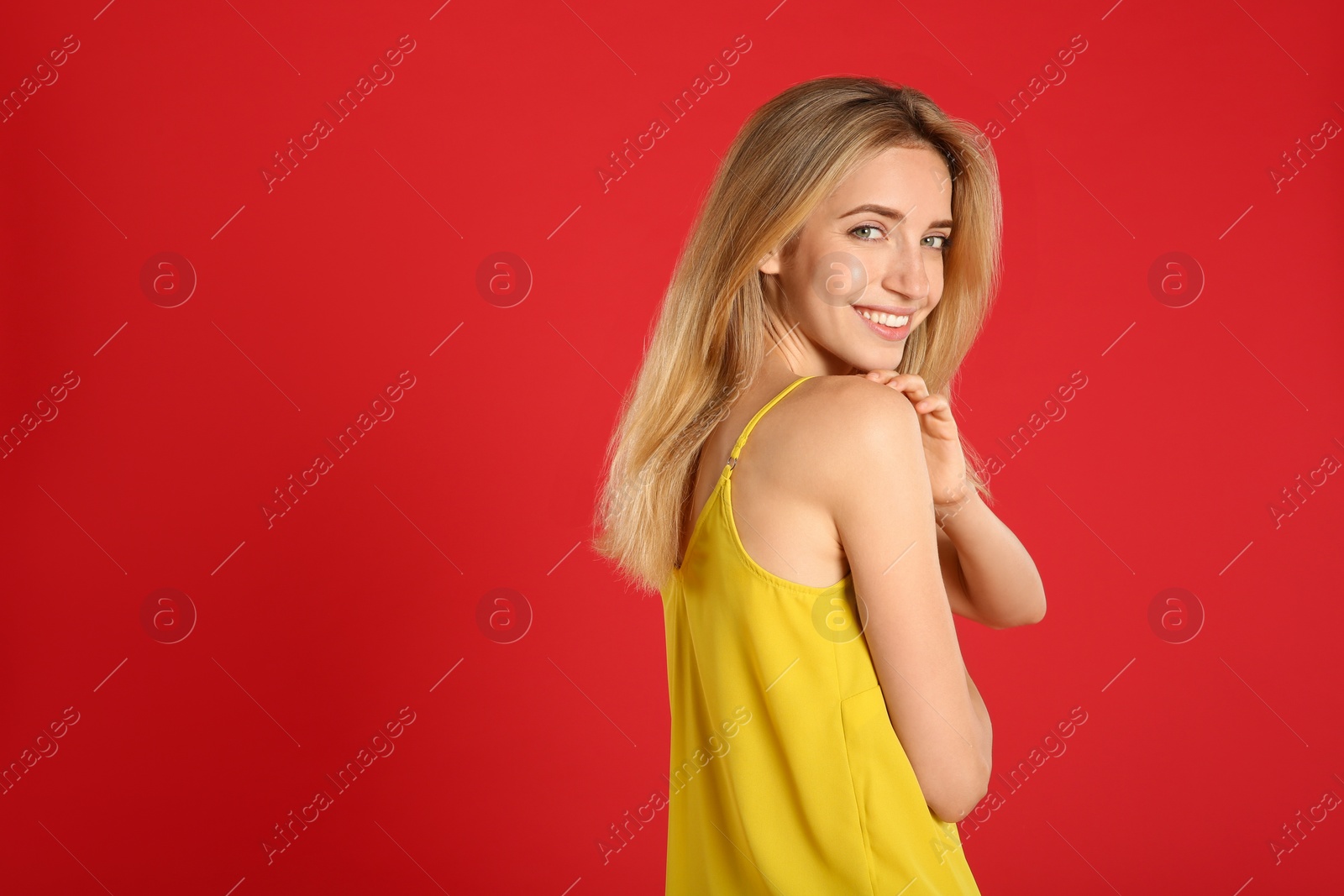Photo of Beautiful young woman with blonde hair on red background. Space for text