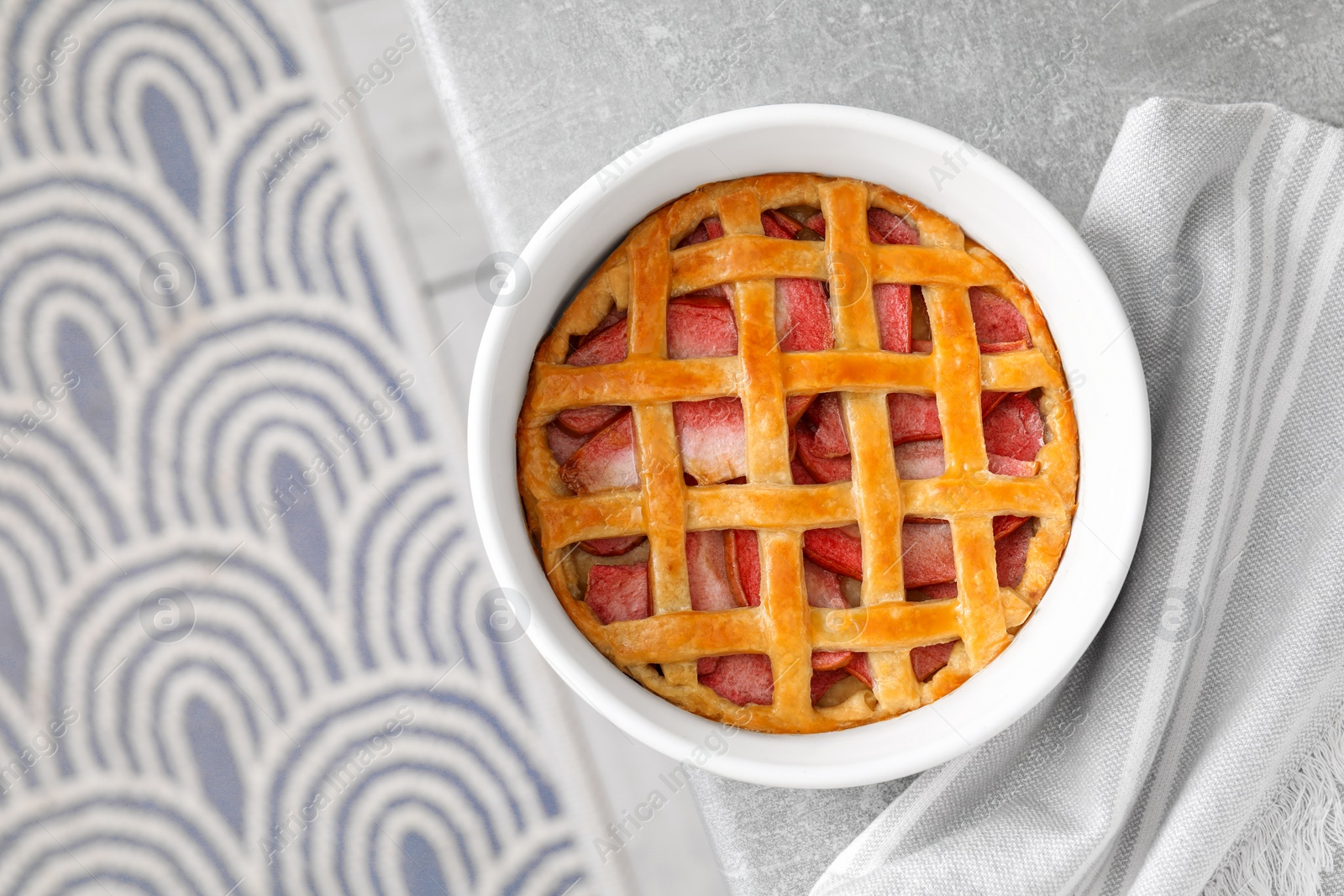 Photo of Baking dish with tasty apple pie on light grey table, top view. Space for text