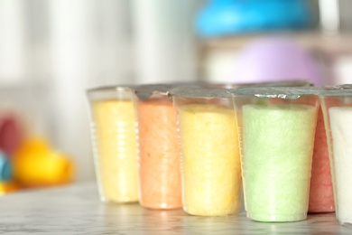 Plastic cups with cotton candy on table against blurred background