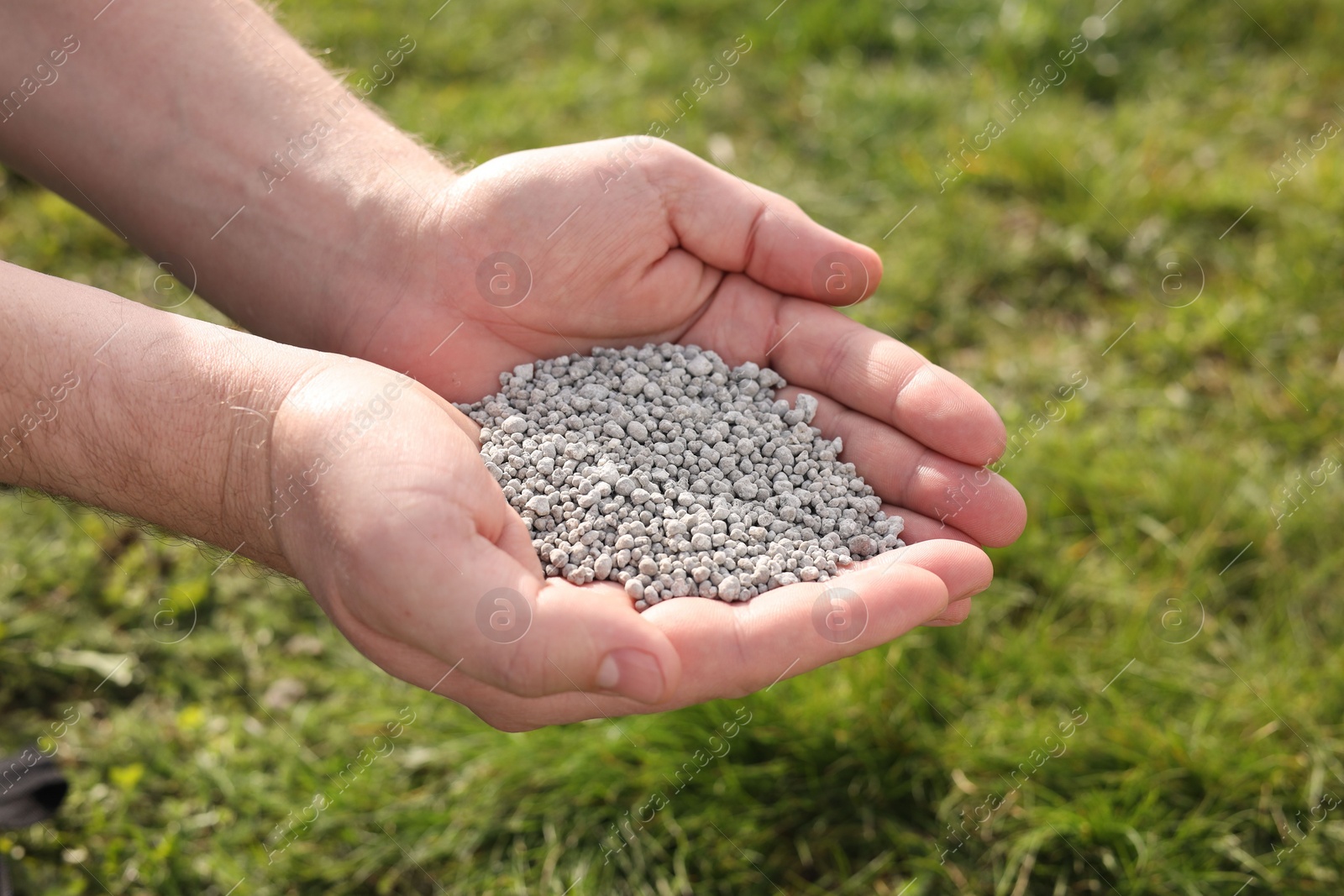 Photo of Man with fertilizer in hands outdoors, closeup